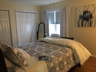 bedroom featuring wood finished floors, baseboards, and two closets