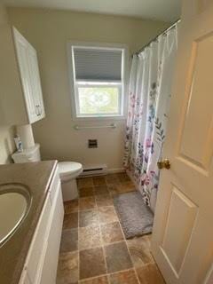 bathroom with vanity, toilet, a shower with shower curtain, stone finish floor, and a baseboard heating unit