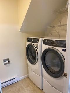 laundry room with baseboards, baseboard heating, laundry area, and washer and clothes dryer