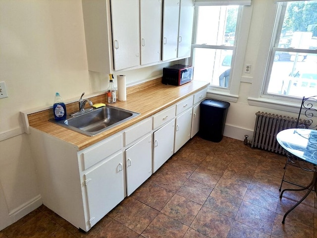 kitchen with white cabinetry, radiator, plenty of natural light, and sink