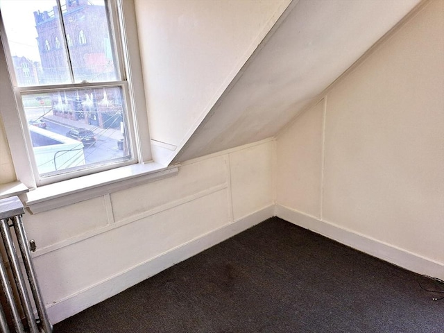 bonus room with dark carpet and vaulted ceiling