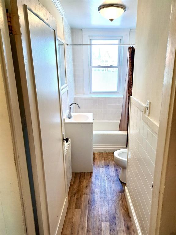 full bathroom with toilet, wood-type flooring, vanity, radiator, and shower / bath combo