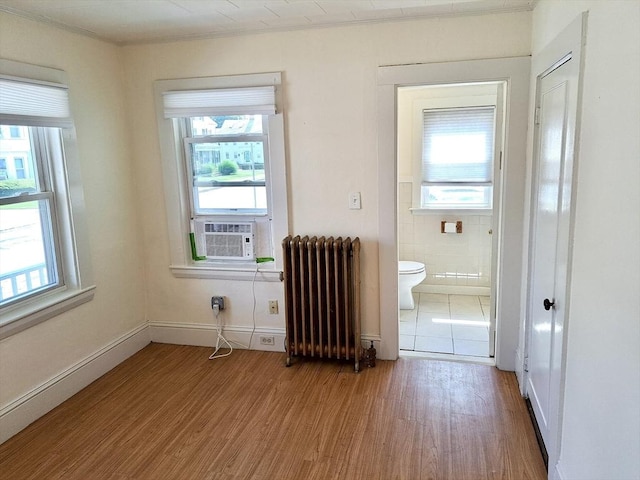 bathroom featuring cooling unit, hardwood / wood-style floors, radiator heating unit, and a healthy amount of sunlight