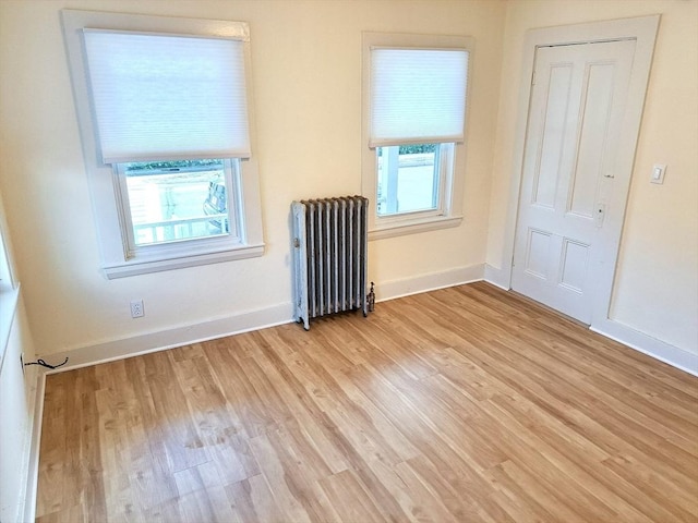 unfurnished room featuring radiator and light hardwood / wood-style flooring