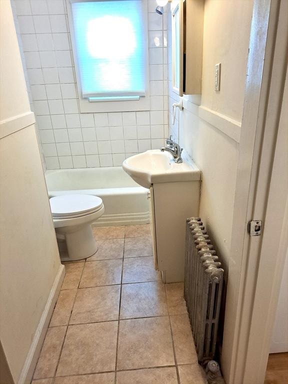 full bathroom with tiled shower / bath, radiator heating unit, vanity, toilet, and tile patterned floors