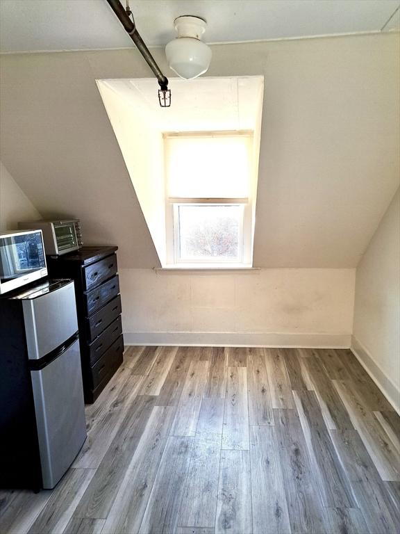 additional living space featuring vaulted ceiling and light wood-type flooring