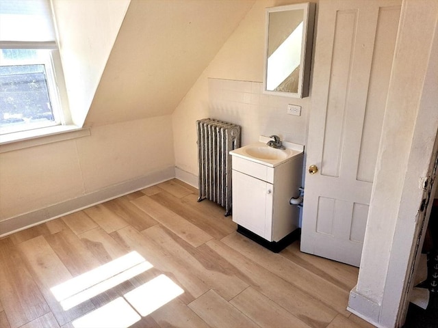 bonus room with light hardwood / wood-style floors, sink, radiator, and vaulted ceiling