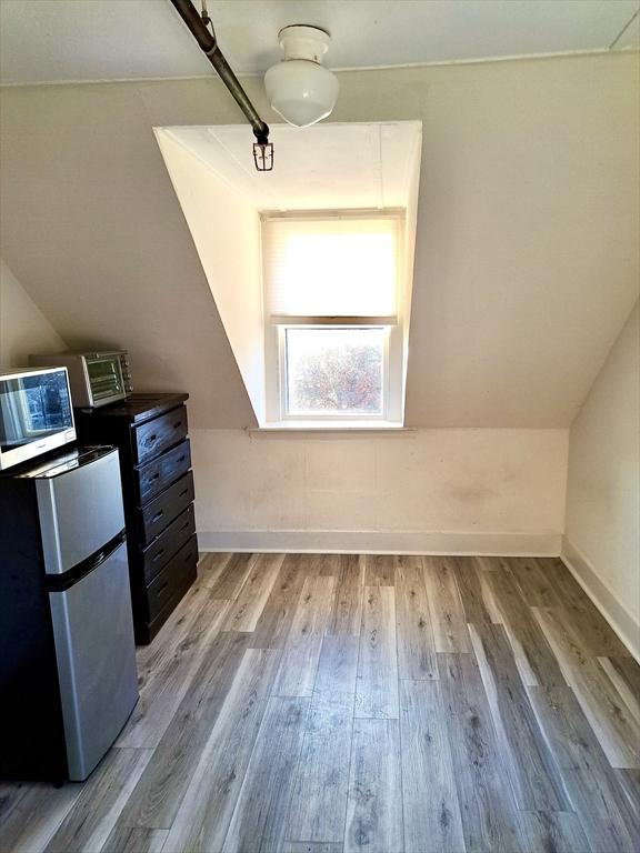 additional living space featuring vaulted ceiling and light hardwood / wood-style flooring