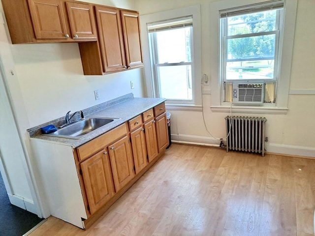 kitchen with cooling unit, sink, radiator, and light hardwood / wood-style floors