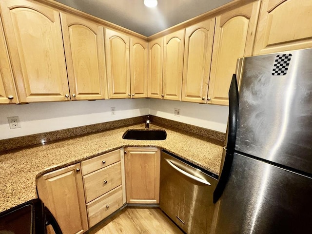 kitchen with stainless steel appliances, sink, light brown cabinets, and light stone counters