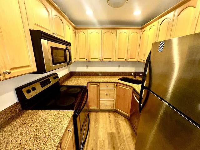 kitchen featuring light stone countertops, appliances with stainless steel finishes, sink, and light brown cabinetry