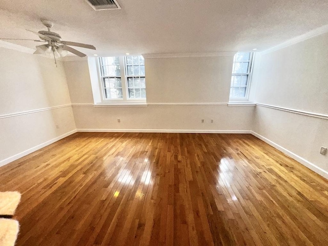 empty room featuring ceiling fan, ornamental molding, hardwood / wood-style floors, and a textured ceiling