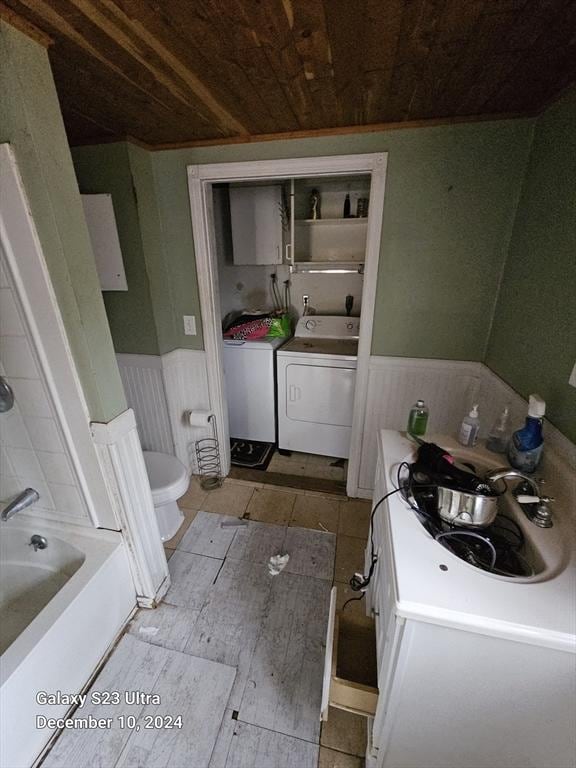 bathroom with washer and clothes dryer, vanity, a bathtub, wooden ceiling, and toilet