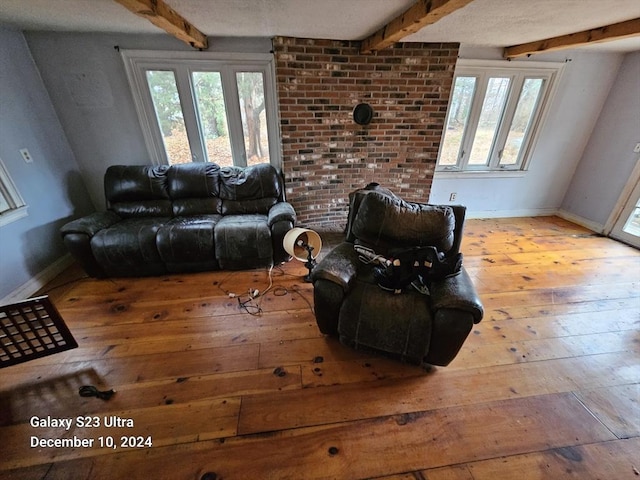 living room with a wealth of natural light, beamed ceiling, and light wood-type flooring