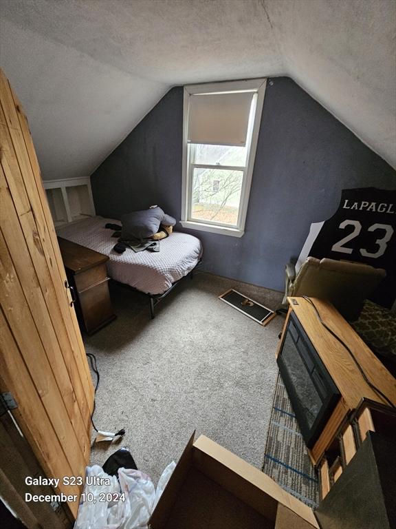 bedroom with a textured ceiling, carpet floors, and vaulted ceiling