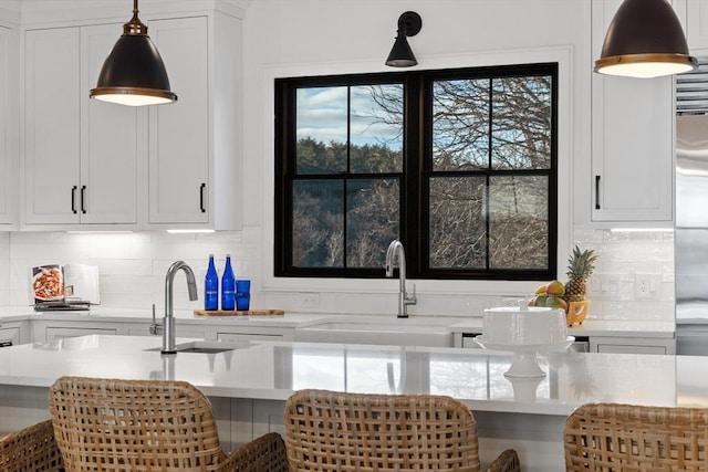 kitchen featuring sink, white cabinetry, decorative light fixtures, and decorative backsplash