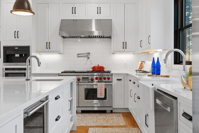 kitchen featuring appliances with stainless steel finishes, white cabinets, wall chimney range hood, and wine cooler