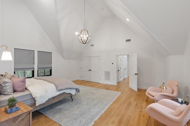 bedroom with light wood-type flooring, an inviting chandelier, and high vaulted ceiling