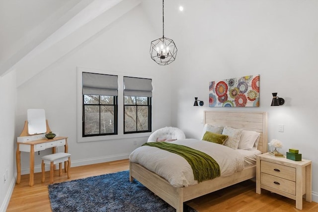 bedroom with light hardwood / wood-style flooring, lofted ceiling, and a chandelier