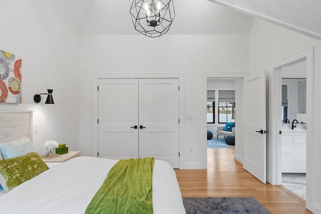 bedroom featuring ensuite bath, a notable chandelier, light hardwood / wood-style floors, and a closet