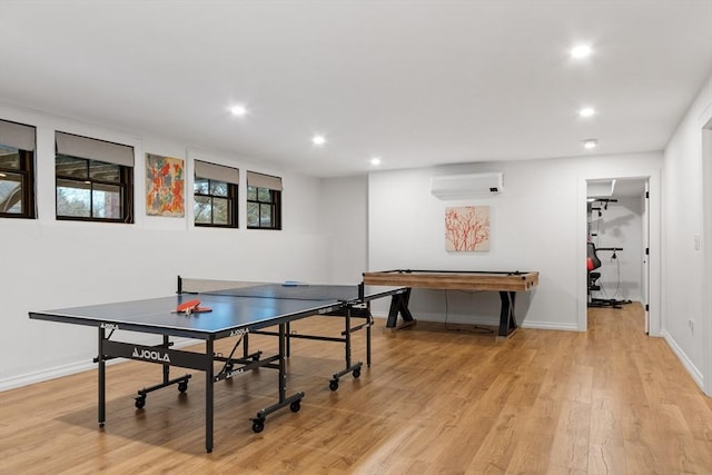 playroom with light hardwood / wood-style floors and an AC wall unit