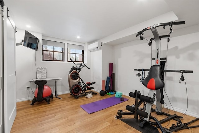 workout area with an AC wall unit and light hardwood / wood-style floors