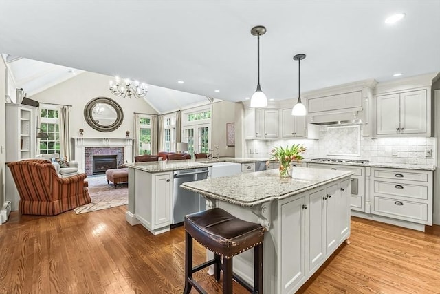21 Fernway, Winchester, MA 01890 - kitchen featuring appliances with stainless steel finishes, open floor plan, a peninsula, a kitchen island, and a brick fireplace