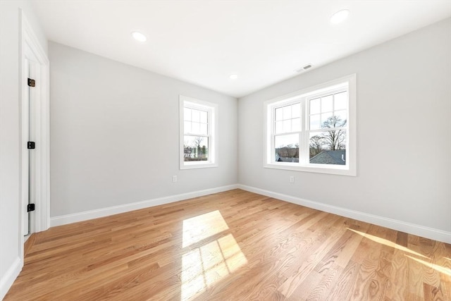 empty room with visible vents, light wood-style flooring, and baseboards