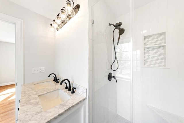 full bathroom featuring tiled shower, wood finished floors, and vanity