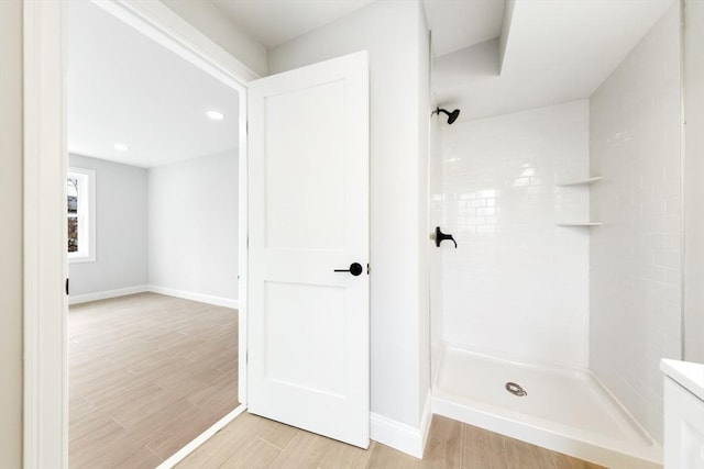 bathroom featuring tiled shower, wood finished floors, and baseboards