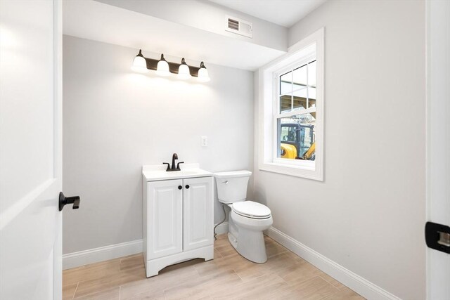 bathroom featuring baseboards, visible vents, toilet, and wood finished floors