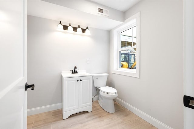 bathroom featuring toilet, wood finished floors, visible vents, and baseboards