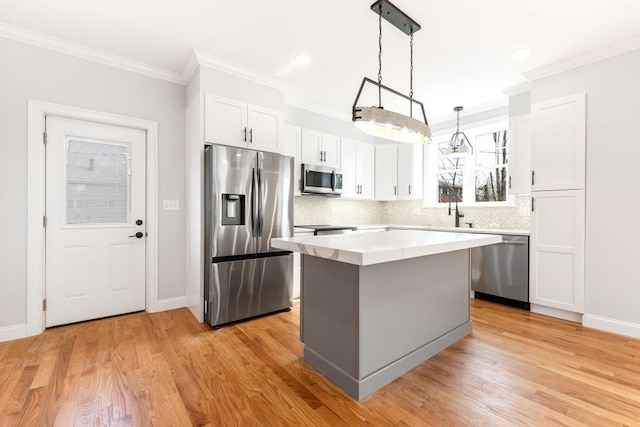 kitchen with ornamental molding, a center island, stainless steel appliances, light wood-type flooring, and white cabinetry