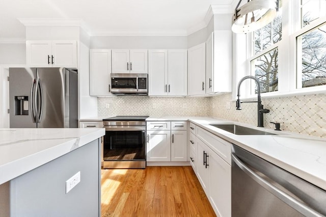 kitchen featuring ornamental molding, appliances with stainless steel finishes, a sink, and white cabinets