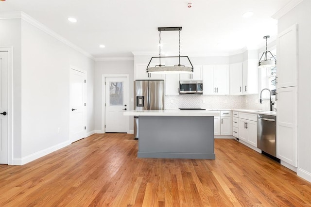 kitchen with stainless steel appliances, ornamental molding, light countertops, and a center island