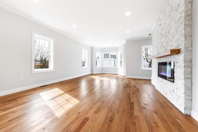 unfurnished living room featuring visible vents, baseboards, crown molding, light wood-style floors, and a fireplace