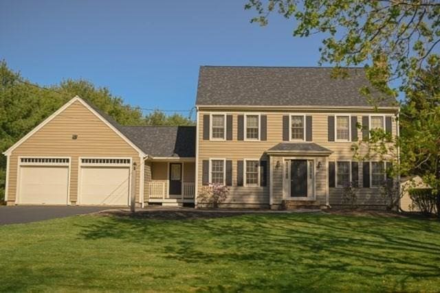 colonial house with an attached garage, driveway, and a front yard