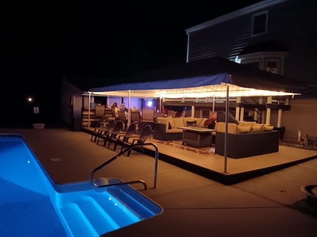 pool at twilight with an outdoor living space, an outdoor pool, and a patio area