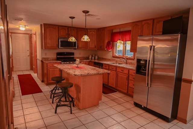 kitchen featuring a center island, light stone countertops, light tile patterned floors, a sink, and stainless steel appliances