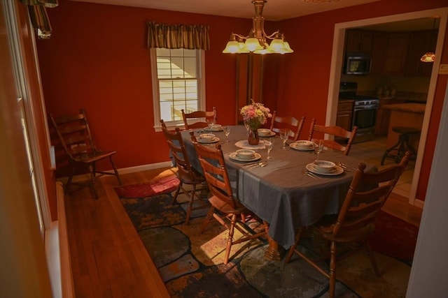dining room featuring baseboards, light wood finished floors, and a notable chandelier