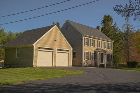 colonial home featuring an attached garage, a front yard, and aphalt driveway