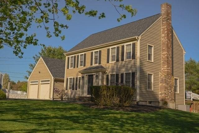 colonial house with a garage, a front lawn, and a chimney