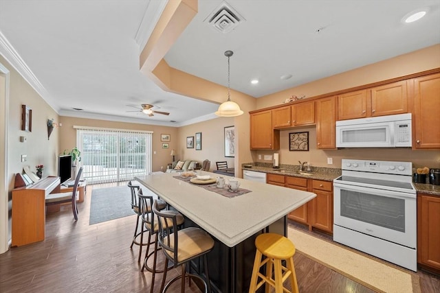 kitchen featuring white appliances, a breakfast bar, a sink, visible vents, and ornamental molding