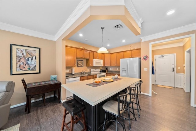 kitchen featuring crown molding, white appliances, wood finished floors, and a kitchen breakfast bar