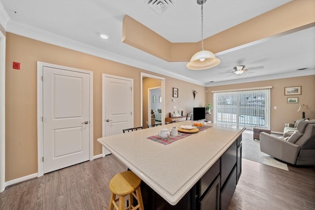 kitchen with open floor plan, light countertops, visible vents, and crown molding