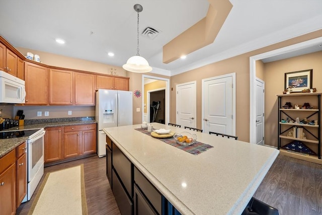 kitchen featuring dark wood finished floors, visible vents, hanging light fixtures, a kitchen island, and white appliances