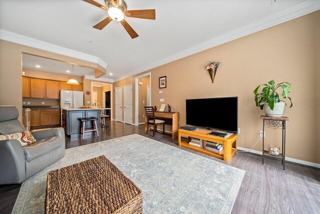 living area with dark wood finished floors, crown molding, recessed lighting, ceiling fan, and baseboards