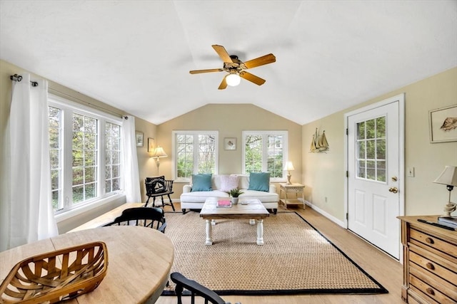 living room featuring ceiling fan, plenty of natural light, light wood finished floors, vaulted ceiling, and baseboards