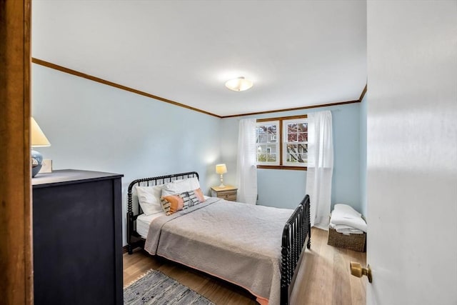 bedroom with ornamental molding and wood finished floors