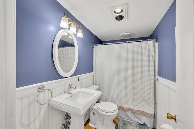 full bathroom featuring wainscoting and toilet
